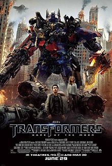 The poster depicts of a Transformer named Optimus Prime, standing with his blade on his left arm, and his blaster on his right arm, with a young couple standing below the Transformer, and standing in front of a crashlanded Decepticon fighter. The characters appear to be in the war-torn city of Chicago, with Decepticon battleships surrounding and guarding the city. The film title and credits are on the bottom of the poster.