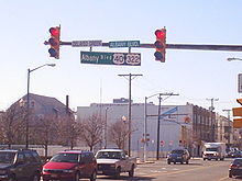 A traffic light pole with a sign on it reading Albany Boulevard U.S. Route 40/U.S. Route 322