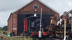 Brick building with steam locomotives in front of it.