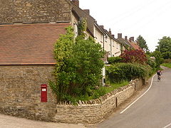 Terrace of houses with plants in front gardens separated from the road by a stone wall.