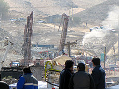 Color photo of San Jose Mine from a distance with several workers in the foreground