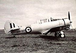 Piston-engined military monoplane parked on grass airfield