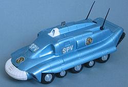 The photograph depicts a scale toy replica of an armoured tank-like vehicle that is metallic-blue in colour, with five wheels on each side.