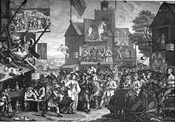 A crowded street populated by characters in 18th century dress.