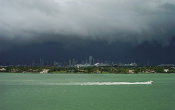 Black rain clouds darken the sky over  tropical waters with the city of Miami in the background.