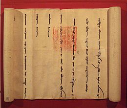 A partially unrolled scroll, opened from left to right to show a portion of the scroll with widely spaced vertical lines of a foreign language. Imprinted over two of the lines is an official-looking square red stamp with an intricate design.