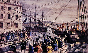 Two ships in a harbor, one in the distance. Onboard, men stripped to the waist and wearing feathers in their hair throw crates of tea overboard. A large crowd, mostly men, stands on the dock, waving hats and cheering. A few people wave their hats from windows in a nearby building.