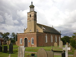 A Georgian style brick church seen from the southwest with a porch protruding in the foreground, a slim tower topped by a rotunda, and the body of the church extending beyond