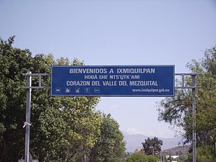 A large overhead road sign says "BIENVENIDOS A IXMIQUILPAN", then (smaller) "HOGÄ EHE NTS'U̲TK'ANI", then (larger again) "CORAZON DEL VALLE DEL MEZQUITAL".
