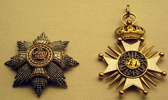 Two jeweled star-burst medallions. One is heavily crusted with carved gold and small gold beads; the other has carved gold, with a central jewel.